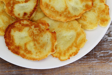 Traditional potato fritters on white plate, closeup
