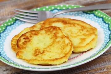 Crispy golden potato fritters on plate, closeup
