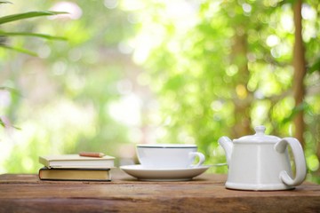 White vintage teapot with with cup and notebooks at outdoor