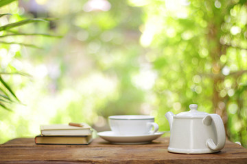 White vintage teapot with with cup and notebooks at outdoor
