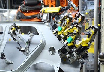 Sheet metal stamped part for the new car in the car factory. The robot holds part for new car.