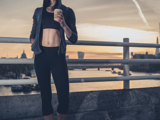 Fototapeta na wymiar Athletic young woman with cup in London at sunrise