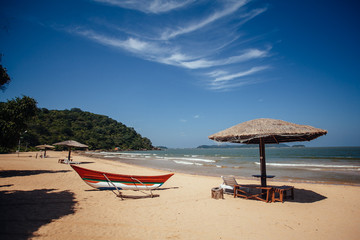 Obraz na płótnie Canvas Beach umbrella on sand next to tropical lagoon. Sun umbrellas and boats on Marble beach, Sri Lanka, Trincomalee