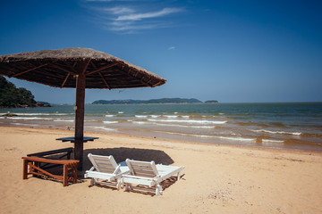 Tropical sand beach with chairs with sun umbrella and cloudy blue sky