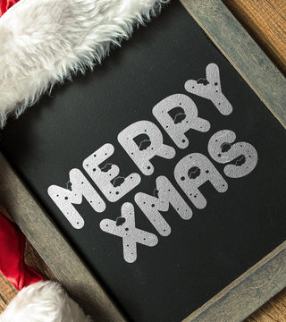 Merry Xmas written on blackboard with santa hat