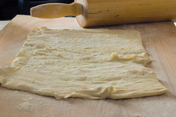 Raw dough roll out the layer on a wooden cutting board