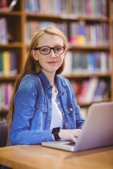 Student with smartwatch using laptop in library