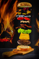 Hamburger stacked high with a juicy beef patty,  with flying ingredients 