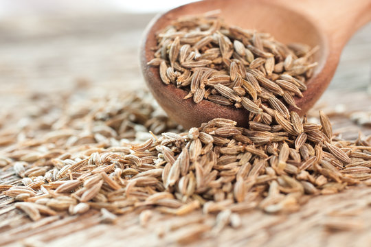 Cumin seeds in a wooden spoon closeup