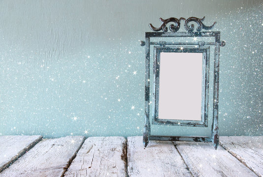 low key image of old victorian steel blue blank frame. vintage filtered image with glitter overlay
