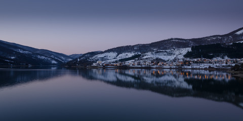Reflejo de un pueblo nevado a las orillas de un lago