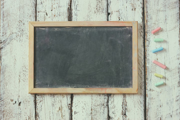 top image of chalkboard and colorfull chalks over wooden table