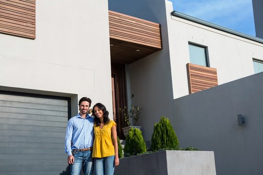 Happy Couple Standing In Front Of New House