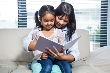 Happy mother reading book with her daughter