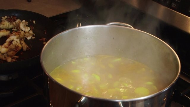 Cooking vegetable soup in pot on kitchen stove