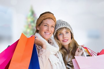 Smiling women looking at camera with shopping bags