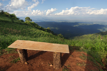 View of a lonely chair, grass, mountain, and cloudy blue sky in Chiangmai city Thailand