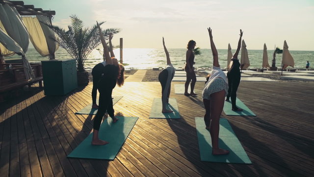 group of women practicing yoga on the beach slow motion