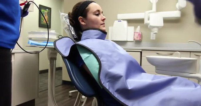 Dentist Chair Raises Up with Patient. camera moves left as dentist pushes button to raise dental chair up with patient.
