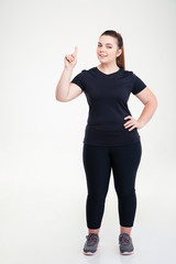 Happy fat woman in sports wear pointing finger up