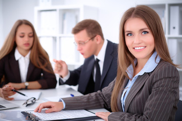 A group of business people at a meeting on the background of office. Focus on a beautiful brunette
