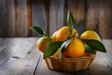 Sweet tangerines in basket on wooden rustic table