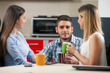Three young businesspeople having a coffee break in an office