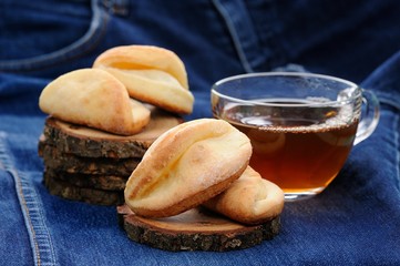 Homemade cookies and black tea on wooden stands on deep blue clo
