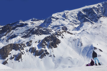 Fototapeta na wymiar Snowboarders pause on a ridge above an off-piste slope in The Three Valleys ski resort, France.