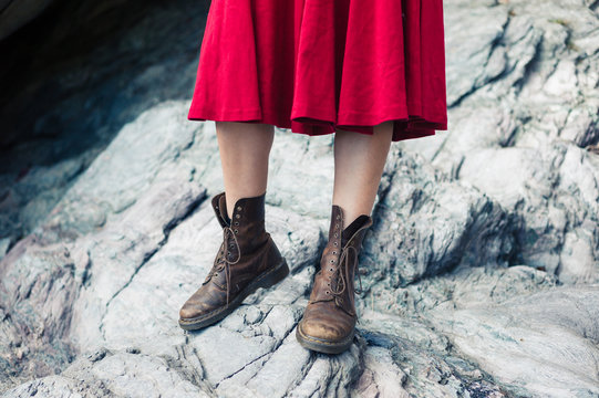 Woman in dress and boots standing on rocks
