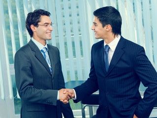Two businesspeople cheering by handshake at office
