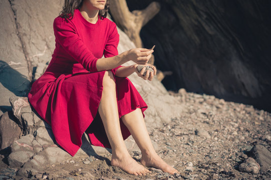 Woman in red dress relaxing by cave on beach