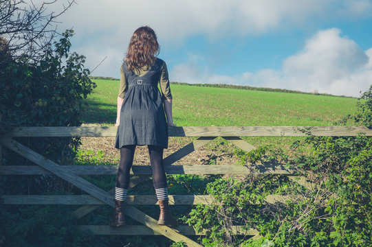 Young woman standing on gate in countryside