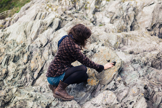 Young woman sitting on rocks and touching stone