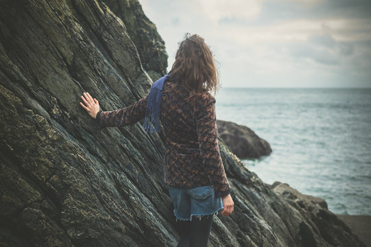 Young woman standing by a rock on the coast