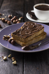 Toast with chocolate paste and nuts on a wooden background