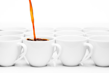 row of white coffee cups with one being filled with hot coffee