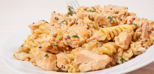 Sliced fried chicken fillet in a creamy and mustard sauce. with fusilli pasta