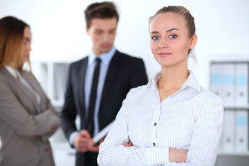 Pretty businesswoman in office with colleagues in the background