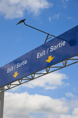 Overhead country border exit sign in English and French.
