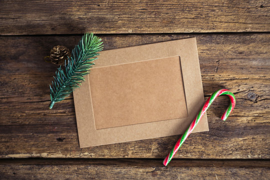 Christmas card on a wooden background with a candy cane, fir branches