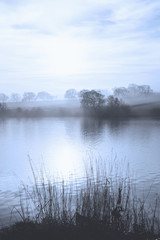 Fototapeta na wymiar Early morning mist over a calm lake in the North Yorkshire Dales, England.
