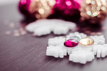 White snowflakes on background of magenta and gold xmas baubles with space for text. Merry christmas. Winter holidays. Xmas theme. Happy New Year. Blurred background.