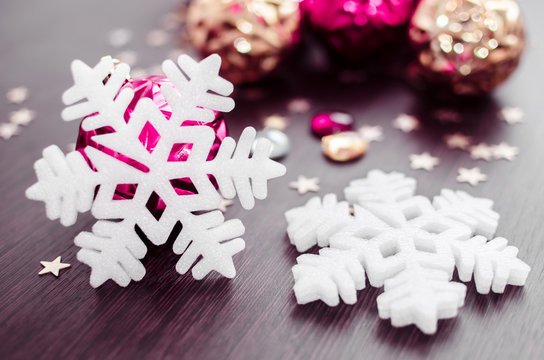 White snowflakes on background of magenta and gold xmas baubles. Merry christmas. Winter holidays. Xmas theme. Happy New Year. Blurred background. - Powered by Adobe