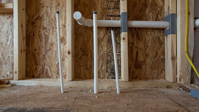 PVC Piping for New Bathroom Construction Dolly. camera moves left on the future site of a bathroom vanity and sink. PVC pipes come up through the floor on this new under construction home
