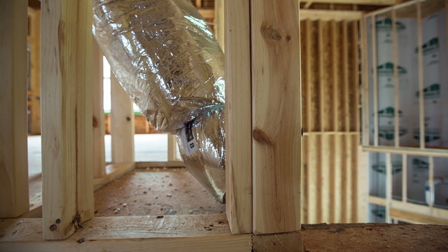Home Building Air Vent Close Up Dolly. camera moves right on a heating and air conditioning vent in a home under construction. bare beams and framing exposed in the open layout type home.
