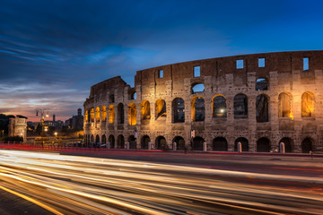 Fototapeta na wymiar Light trails pass the Colosseum in Rome at dusk
