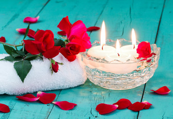 Spa composition of red roses and aroma candles  teal blue background