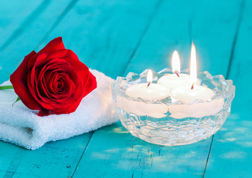 Spa Composition Of Single Red Rose And Aroma Candles On Teal Blue Background