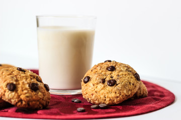 Chocolate chip cookies and milk on a red tablecloth